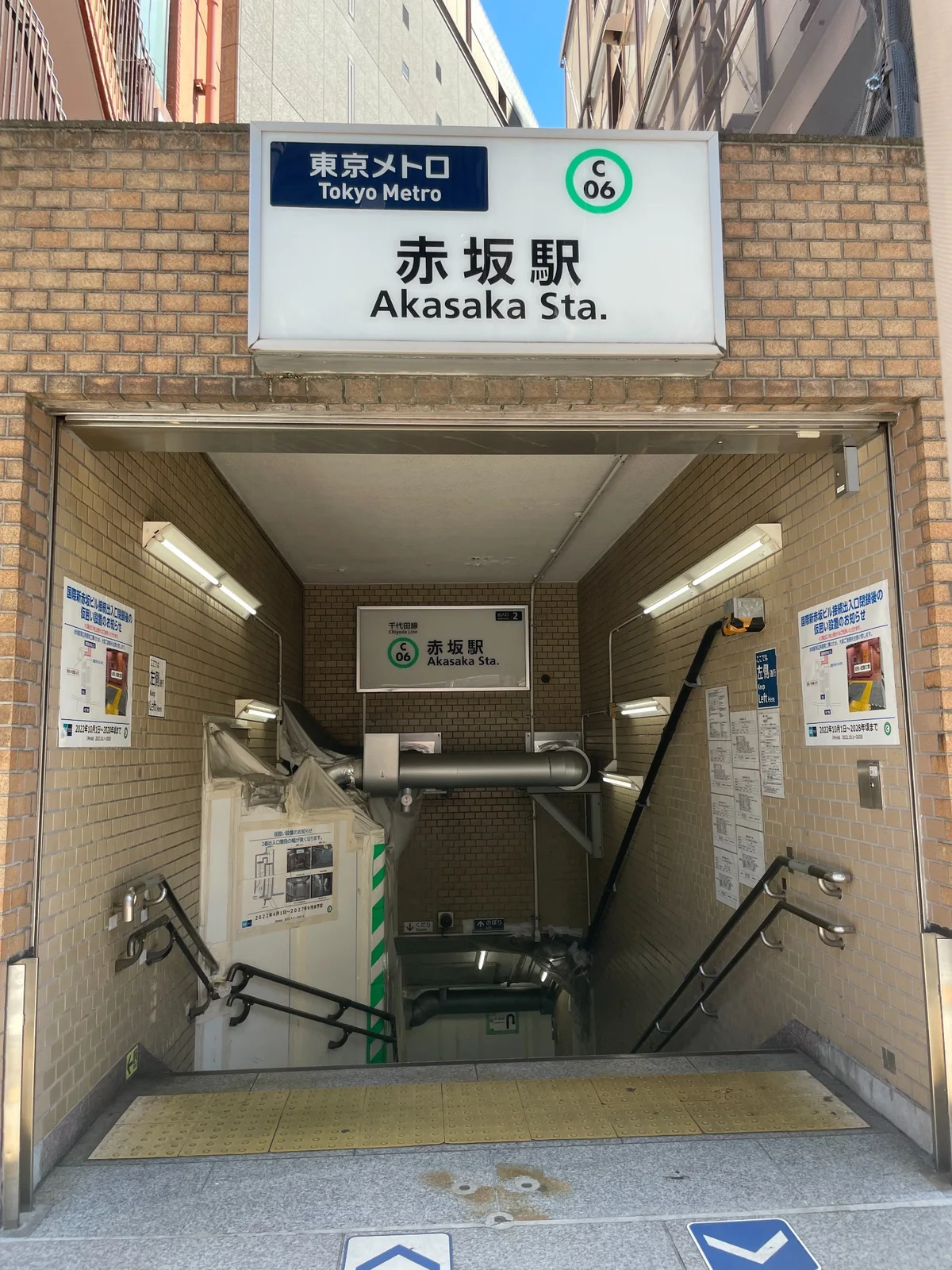 「東京メトロ 赤坂駅 Akasaka Sta.」と表示された地上出入口の看板と、地下へ続く階段