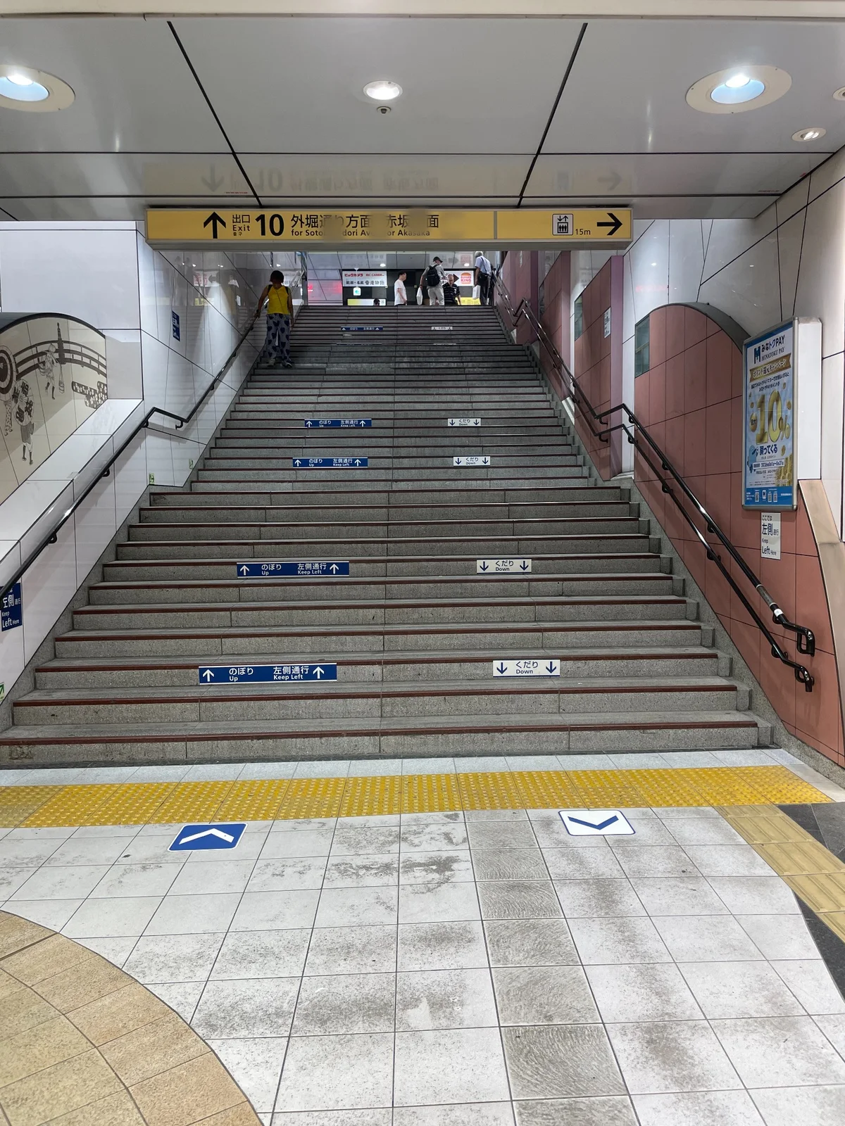 駅構内の階段と、上部の黄色い案内看板「出口 10 外堀通り方面 赤坂方面」
