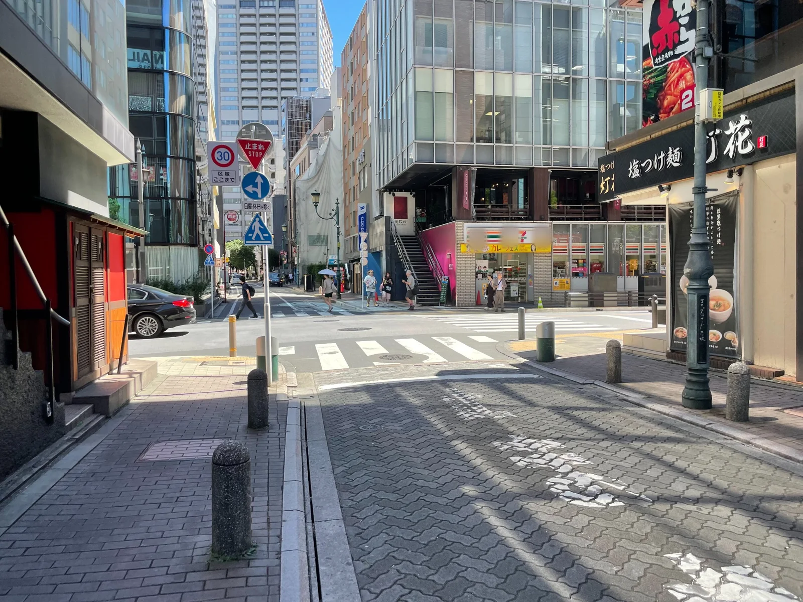 「止まれ STOP」の標識がある交差点と横断歩道。正面の角にコンビニエンスストア
