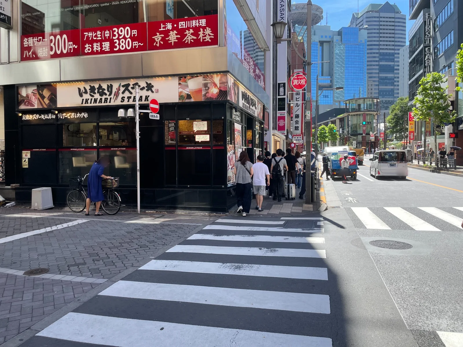 1階に「いきなり！ステーキ」、2階に「上海・四川料理 京華茶楼」の看板がある建物の角と横断歩道