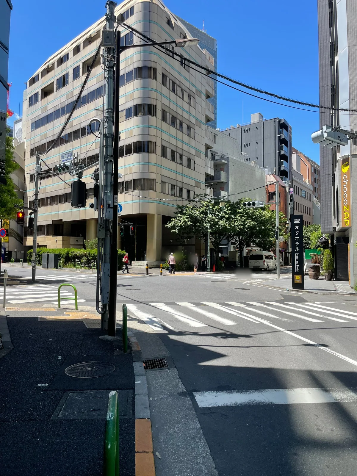 信号のある交差点と横断歩道。正面に曲面の外壁を持つ淡い色のビル