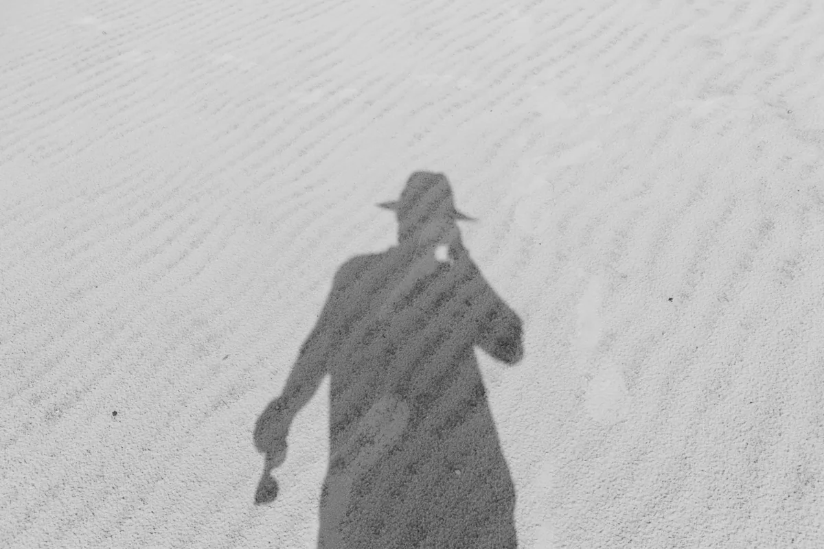 路上に伸びる人影のモノクロ写真