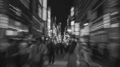 夜の街を行き交う人の流れをとらえたモノクロ写真
