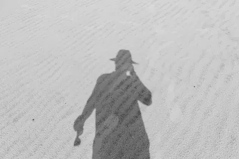 路上に伸びる人影のモノクロ写真